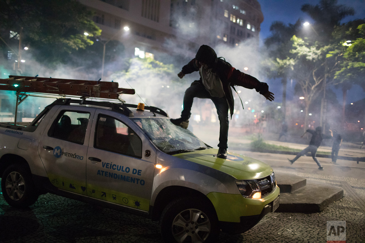 A demonstrator breaks the windshield of a truck that belongs to a subway maintenance crew after clashes with police broke out during a general strike in Rio de Janeiro, Brazil, Friday, April 28, 2017. Public transport largely came to a halt across much of Brazil on Friday and protesters blocked roads and scuffled with police as part of a general strike to protest proposed changes to labor laws and the pension system. (AP Photo/Leo Correo)