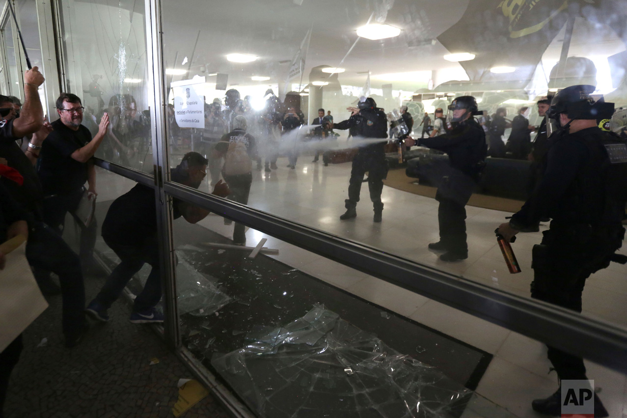 Police officers attempt to break into the Brazilian National Congress during a protest by police officers from several Brazilian states against pension reforms proposed by Brazil's President Michel Temer's government that would end the special pension retirement of police officers, in Brasilia, Brazil, Tuesday, April 18, 2017. (AP Photo/Eraldo Peres)