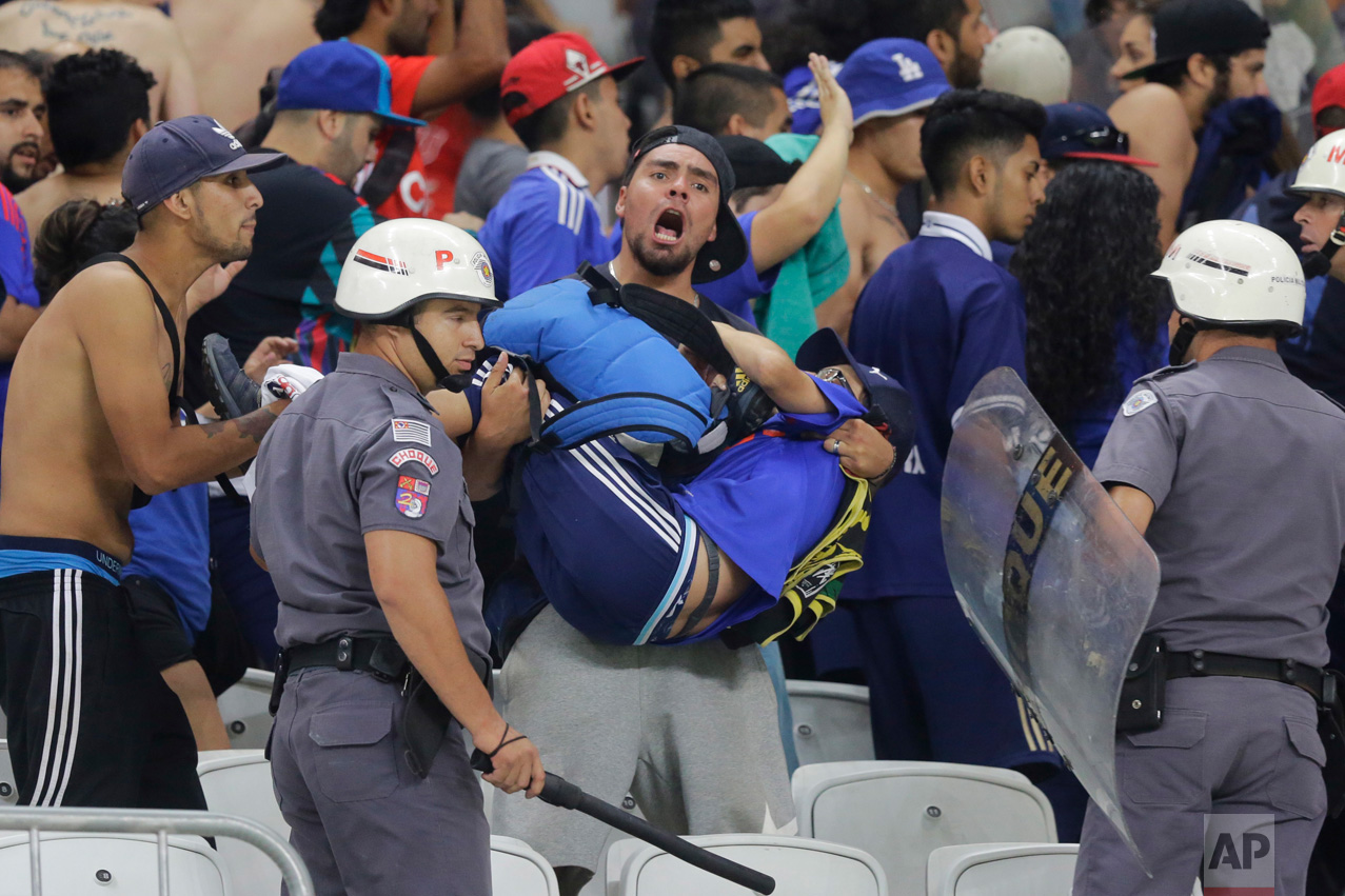 A fan of Universidad de Chile carries a mate that collapsed when they clashed with the police during a Copa Sudamericana soccer match against Brazil's Corinthians in Sao Paulo, Brazil, Wednesday, April 5, 2017. (AP Photo/Nelson Antoine)