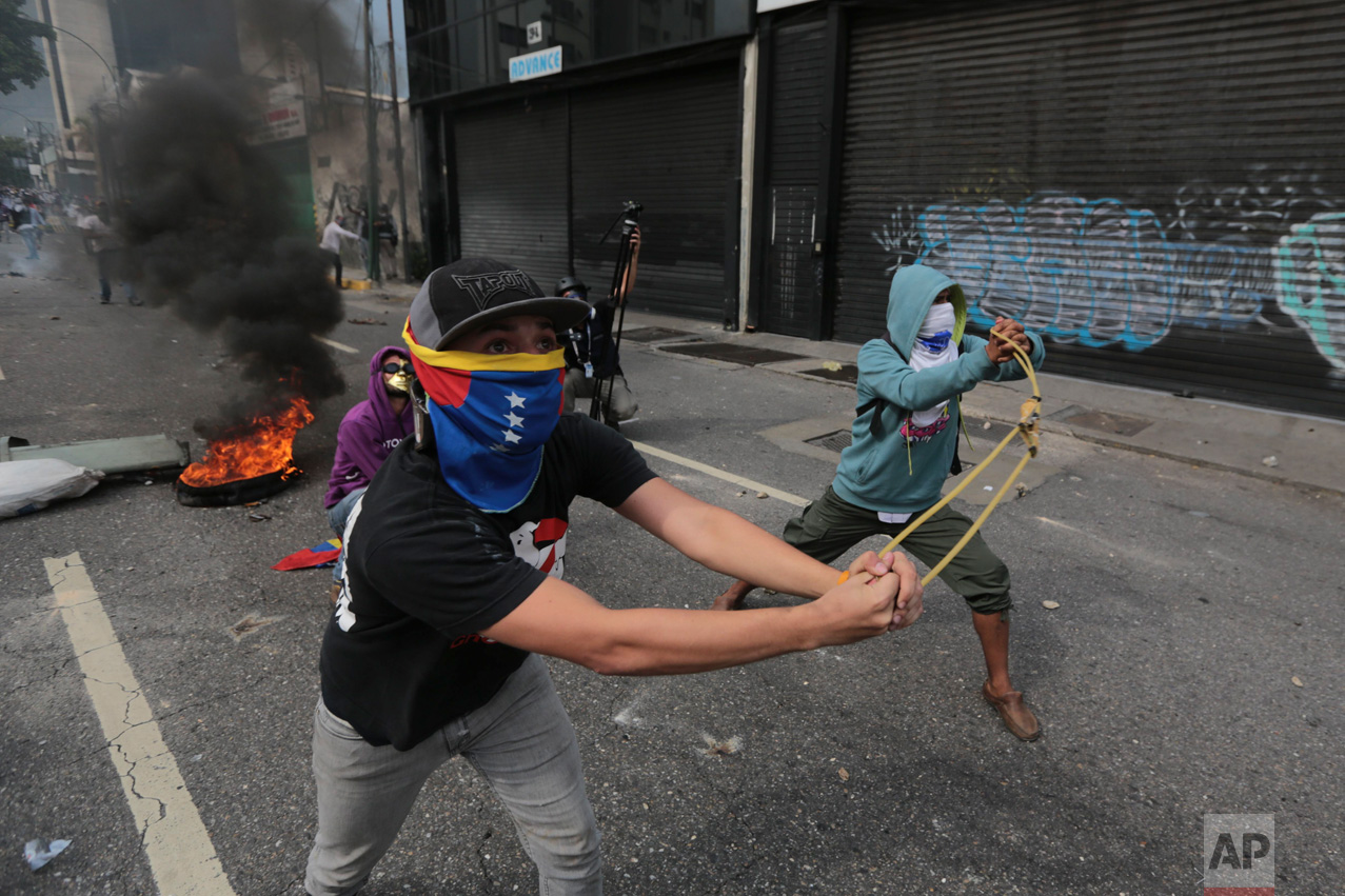 Anti-government protesters launch stones with a sling during clashes in Caracas, Venezuela, Wednesday, April 19, 2017. Tens of thousands of opponents of President Nicolas Maduro flooded the streets of Caracas in what's been dubbed the "mother of all marches" against the embattled socialist president. (AP Photo/Fernando Llano)