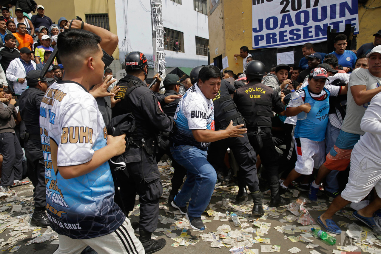  In this Monday, May 1, 2017 photo, soccer fans force themselves past police during an interval between games at the Little World Cup of Provenir street soccer championship in Lima, Peru. Dozens of teams bring their fans to defend each goal, even if 