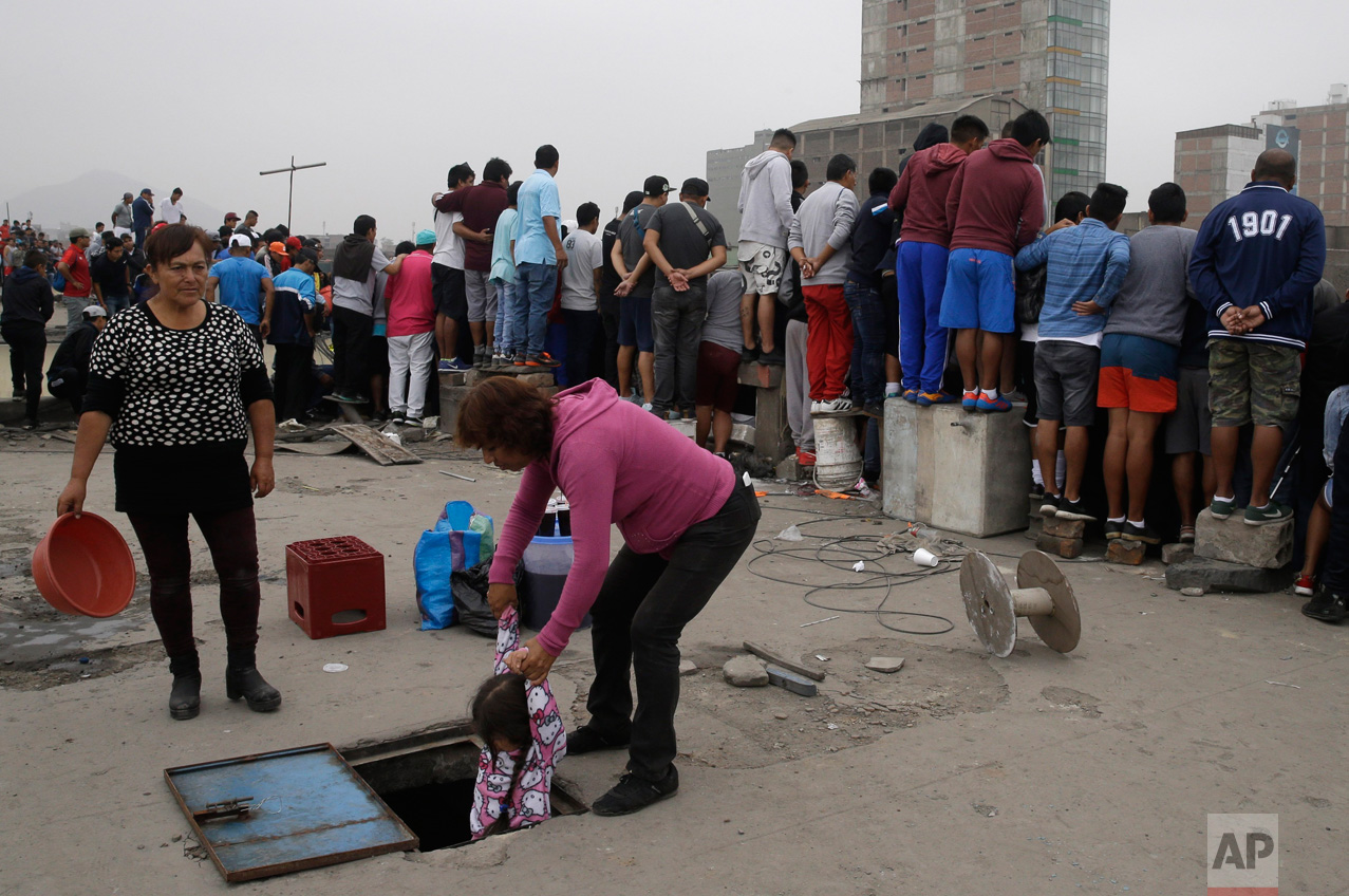  In this Monday, May 1, 2017, a woman helps a little girl down from a rooftop where fans watch the Little World Cup of Provenir street soccer championship in Lima, Peru. Spectators pay $2 dollars for a balcony view in apartment buildings to catch the