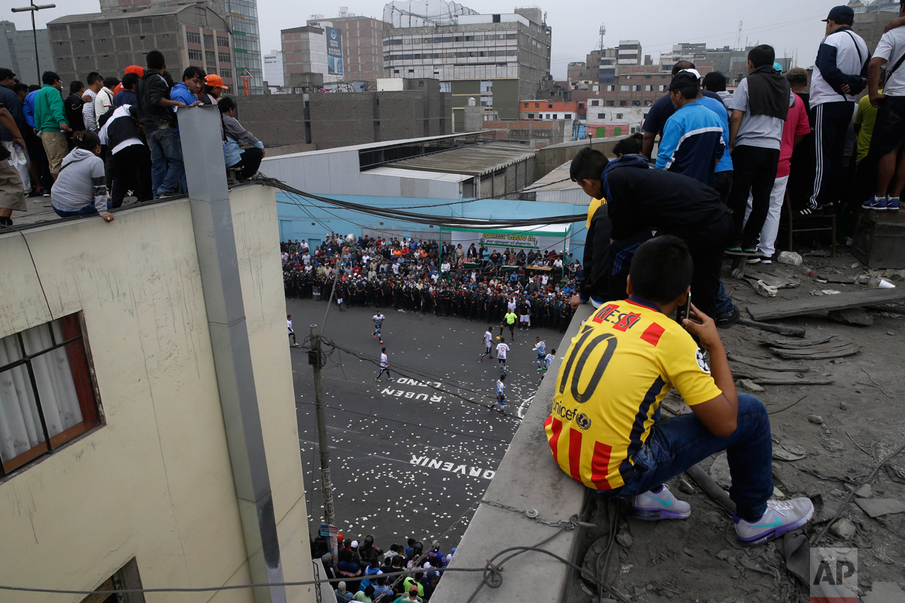  In this May 1, 2017 photo, people watch the Little World Cup of Provenir street soccer championship from an apartment roof top, for which they pay about $2 dollars, in Lima, Peru. To score good seats, people camp out the night before, lining the roa