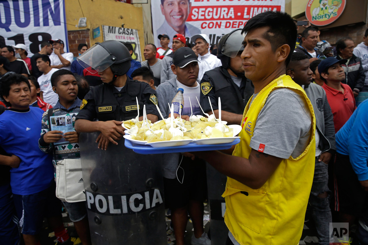  In this Monday, May 1, 2017, a food vendor works the crowd during a break at the Little World Cup of Provenir street soccer championship in Lima, Peru. His tray is filled with plates of baked potatoes, boiled eggs and a spicy cream. (AP Photo/Martin
