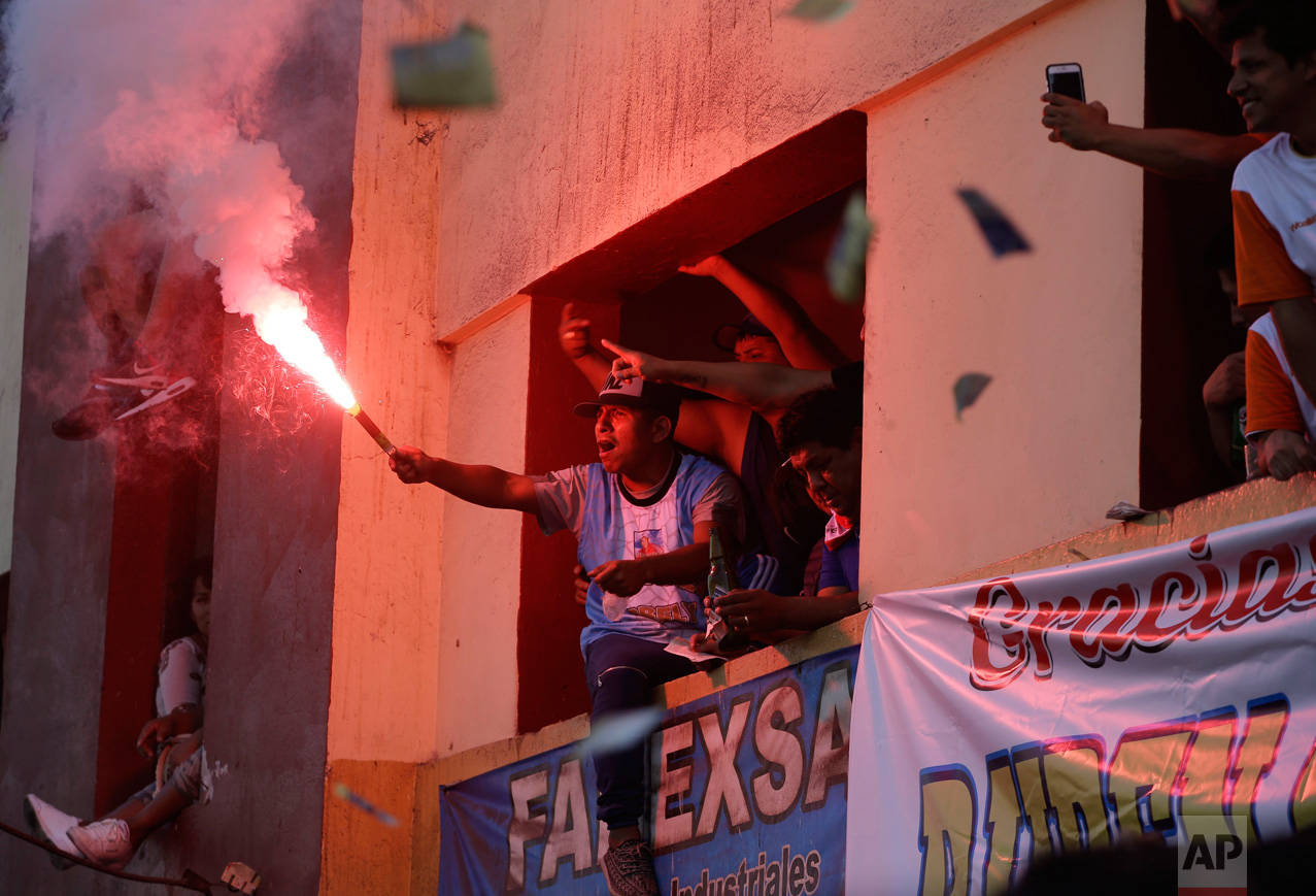  In this Monday, May 1, 2017 photo, a soccer fan lights a flare from an apartment building balcony overlooking the Little World Cup Porvenir street soccer championship in Lima, Peru. The working-class neighborhood ritual in El Porvenir began in the 1