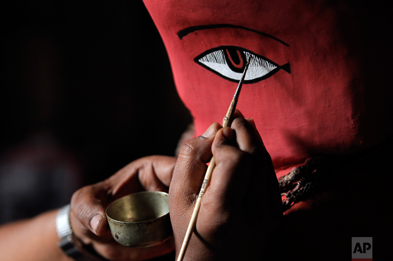  In this April 23, 2017, photo, a Chitrakar artist paints details on the statue of Rato Machindranath in Machindra Bahal in Lalitpur, Nepal. The wide-eyed statue of Machindranath, made from red-painted clay and covered with gold ornaments, is kept un