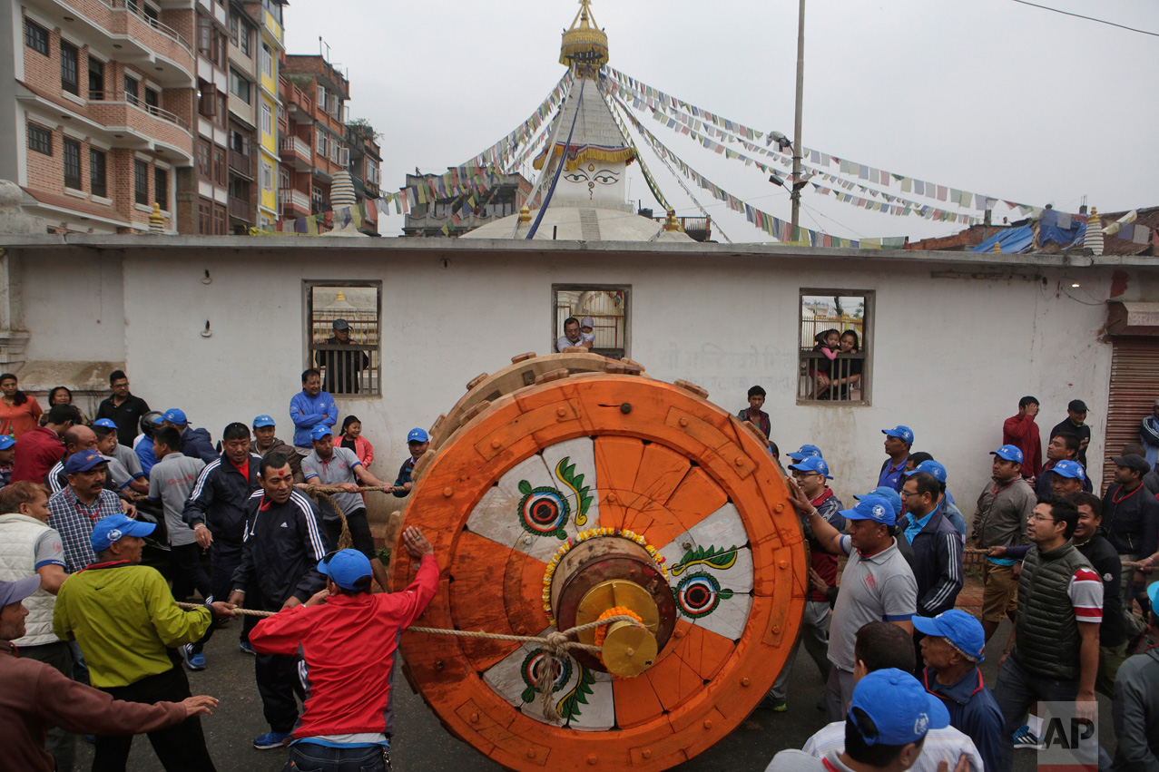  In this April 21, 2017, photo, locals and members of the Barahi community roll out a wheel to the construction site of the Rato Machindranath Chariot in Lalitpur, Nepal. The Barahis are responsible for repairing the giant wheels, carving the base an