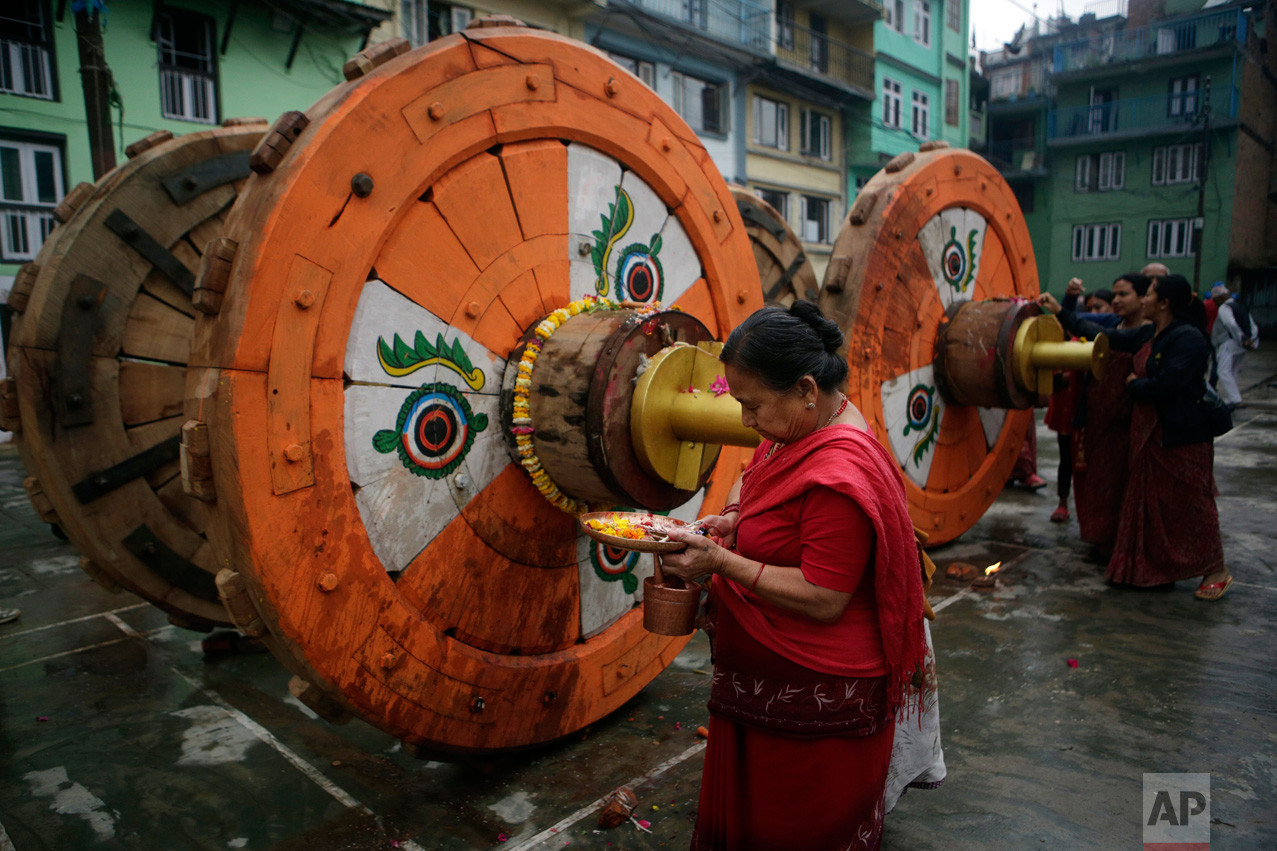  In this April 21, 2017, photo, a Hindu woman performs ritual prayers in front of wheels that will be assembled for the Rato Machindranath Chariot in Lalitpur, Nepal. The chariot built every year is 15-meter (48-foot) tall and based on a chassis that