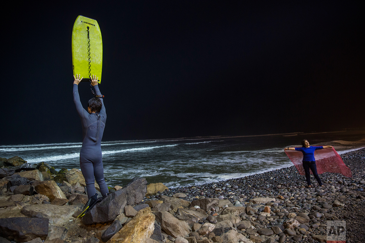  In this April 21, 2017 photo, Renato de Negri, 15, lifts his boogie board to signal to a fellow surfer in Pacific Ocean waters that he has returned to shore, at La Pampilla beach, in Lima, Peru. Pampilla beach does not attract sharks, unlike some be