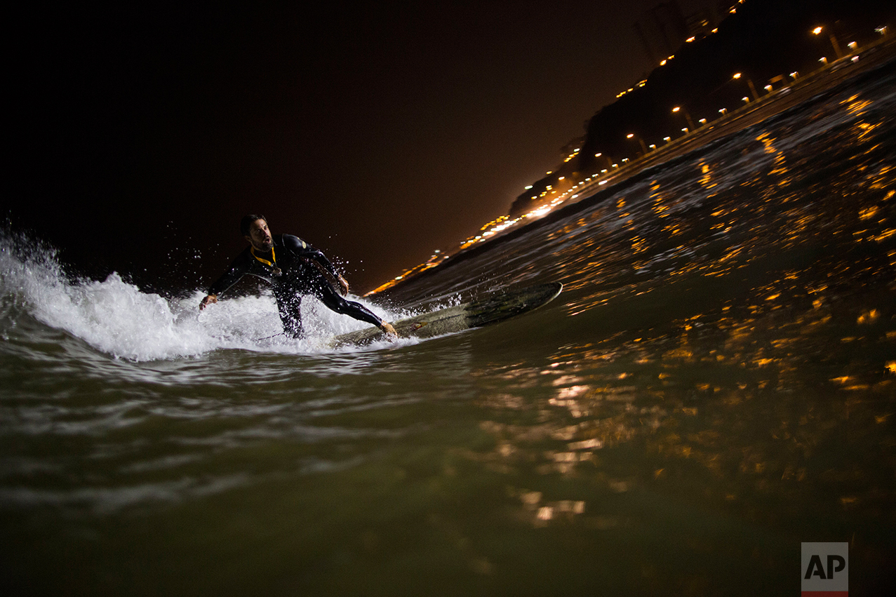  In this April 26, 2017 photo, Ernesto Benavides rides a wave in the waters of La Pampilla beach in Lima, Peru. As most Lima residents prepare to sleep, a handful of hardcore surfers descend on the only beach in Peru where they can ride the waves at 