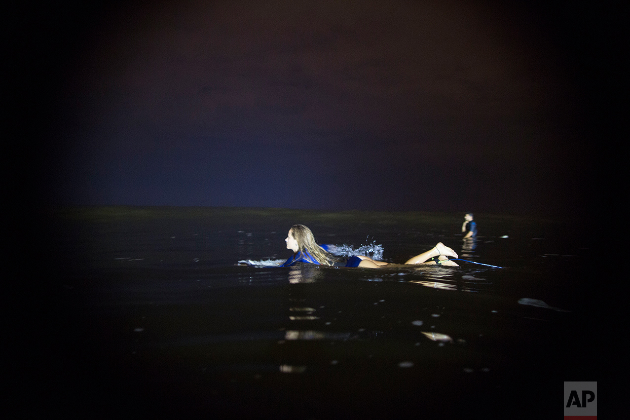  In this March 15, 2017 photo, Marie Schoene looks for a wave to surf in La Pampilla beach in Lima, Peru. Pampilla does not attract sharks, unlike some beaches in the United States and Australia. The greatest danger faced by night surfers is that the