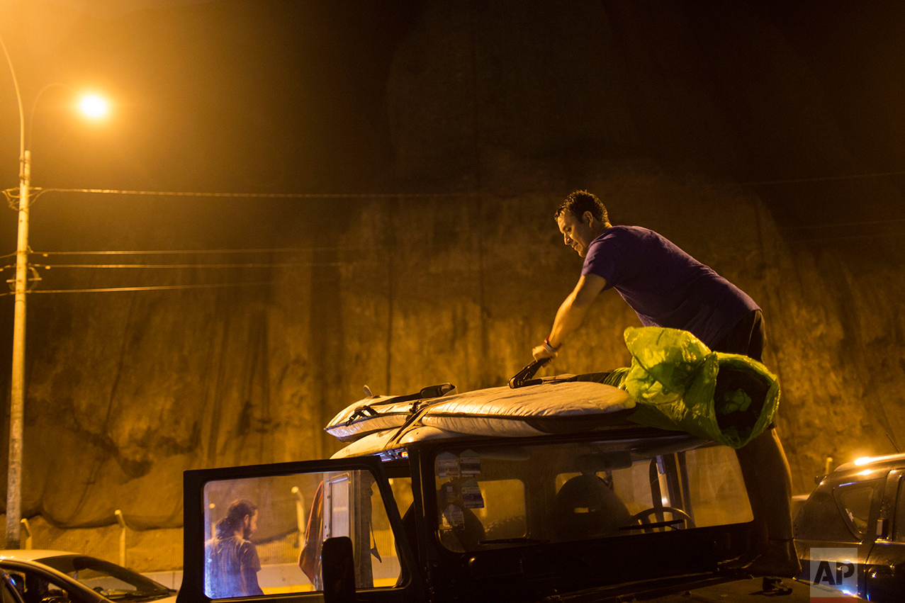  In this March 1, 2017 photo, surfer Mario Razzeto accommodates his board on the roof of a car after surfing in the waters of La Pampilla beach in Lima, Peru. Pampilla is the second beach in Latin America set up for night surfing. The Brazilian beach