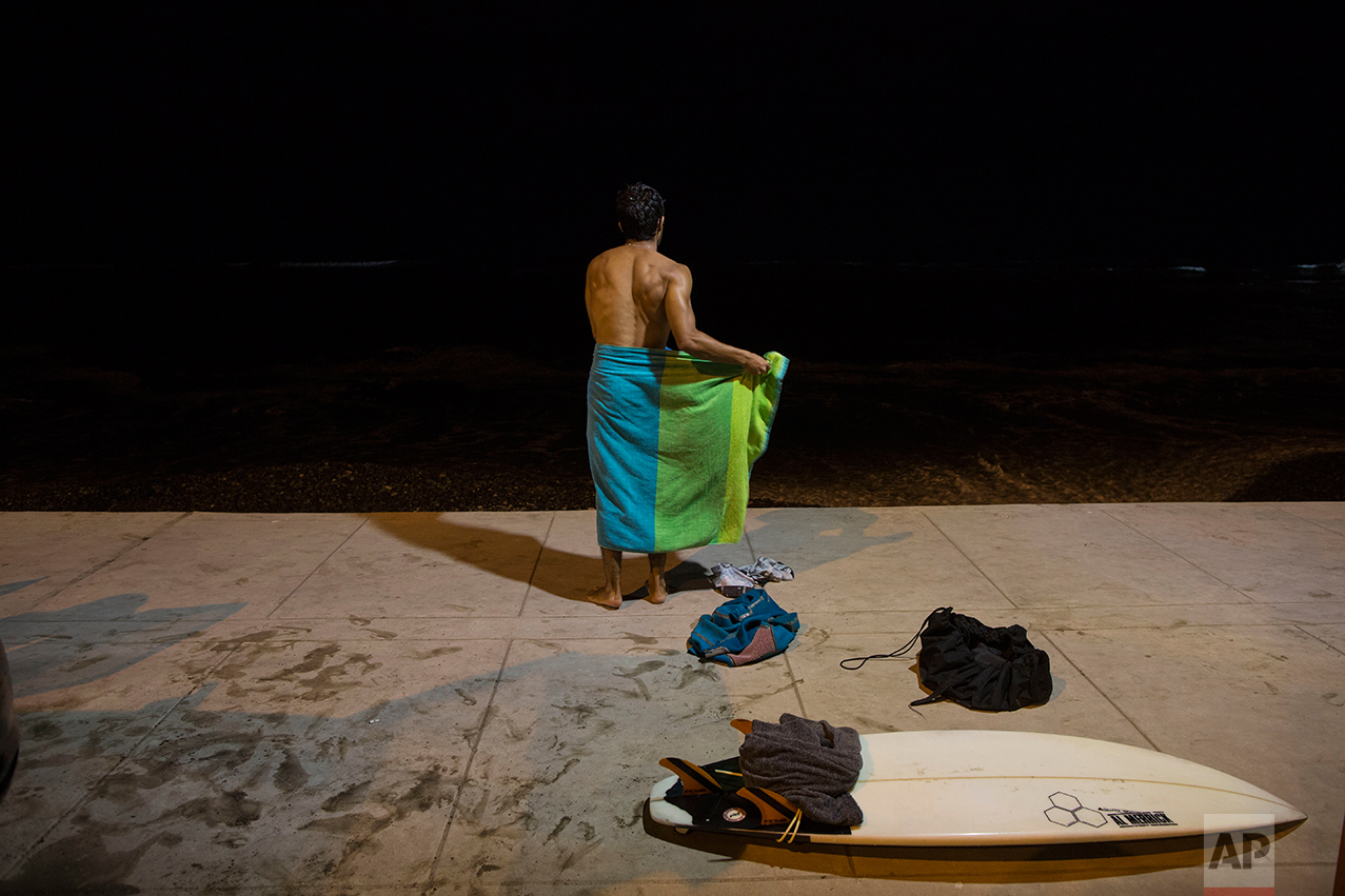  In this March 3, 2017 photo, a man wraps a towel around his waist after a night of surfing at La Pampilla beach in Lima, Peru. As most Lima residents prepare to sleep, a handful of hardcore surfers descend on the only beach in Peru where they can ri