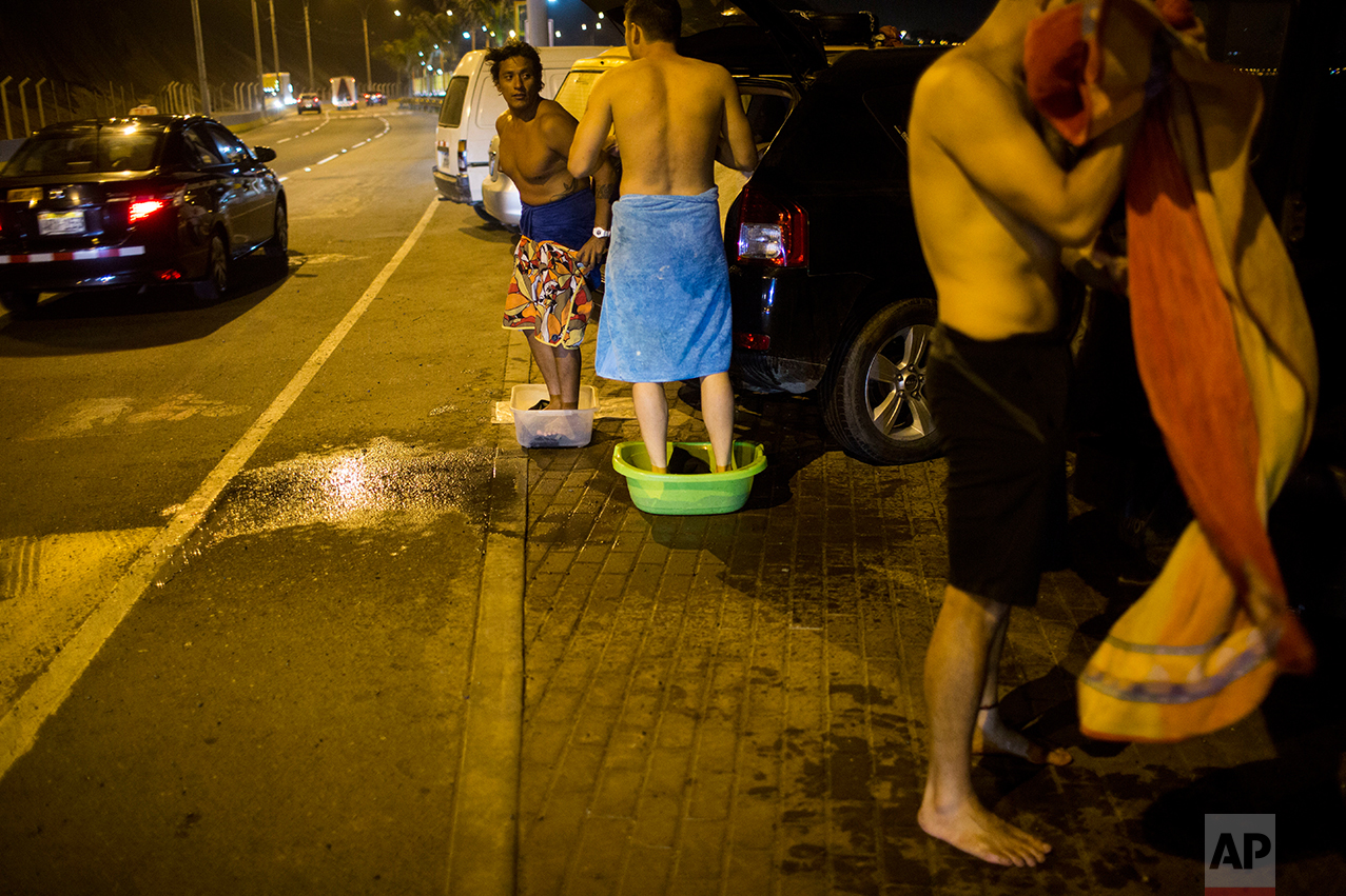  In this March 1, 2017 photo, surfers stand in tubs to catch the sand and salt water they rinse off their bodies before getting into their vehicles, at La Pampilla beach in Lima, Peru. The beach attracts fewer than two dozen surfers a night. (AP Phot