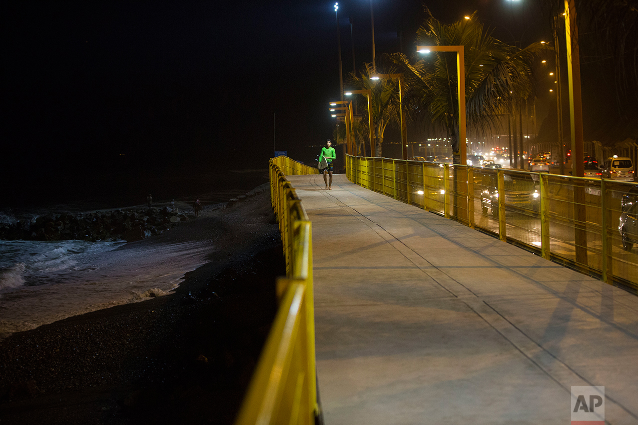  In this March 1, 2017 photo, a surfer walks along the promenade that lines La Pampilla beach in Lima, Peru. The Andean country has decked out Pampilla with four 1,000-watt light like those used in soccer stadiums, providing enough illumination to su