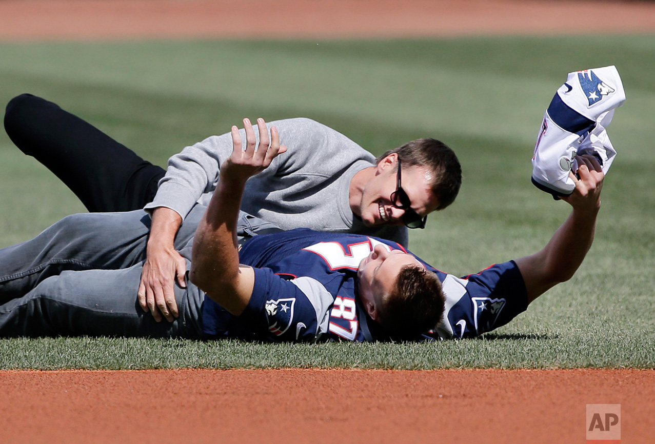  New England Patriots quarterback Tom Brady, top, tackles teammate Rob Gronkowski after he ran with Brady's recovered Super Bowl jersey as they joke around during Boston Red Sox Home Opening Day ceremonies at Fenway Park, Monday, April 3, 2017, in Bo