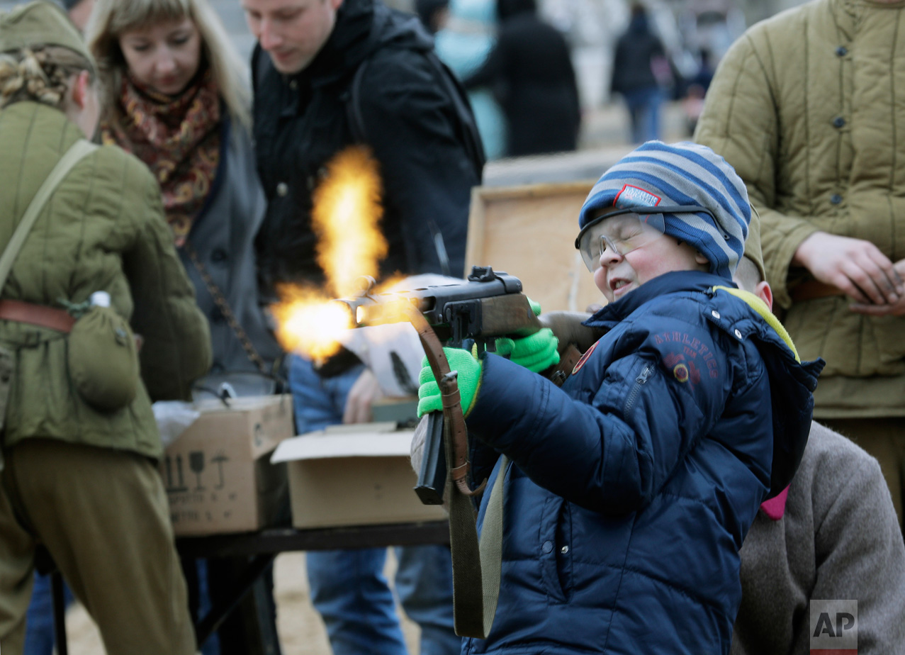  A boy shoots a World War II-era machine gun armed with blanks at a weapon exhibition during a military show in St. Petersburg, Russia, on Sunday, April 30, 2017. (AP Photo/Dmitri Lovetsky) 