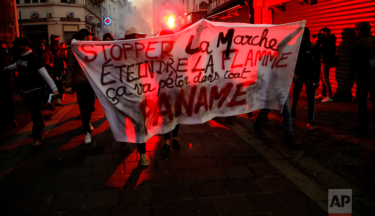  Protesters march with lit flares holding a banner that reads on top "Stop La Marche" in reference to Emmanuel Macron and on second row "Put out the Flame" in reference to Marine Le Pen while bottom row reads "This will explode all over Paris" during