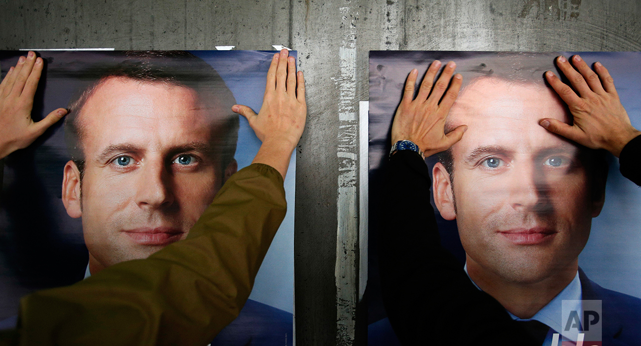  A supporter of French centrist presidential candidate Emmanuel Macron puts up a campaign poster, in Lille, northern France, Tuesday, May 2, 2017.  (AP Photo/Michel Spingler) 