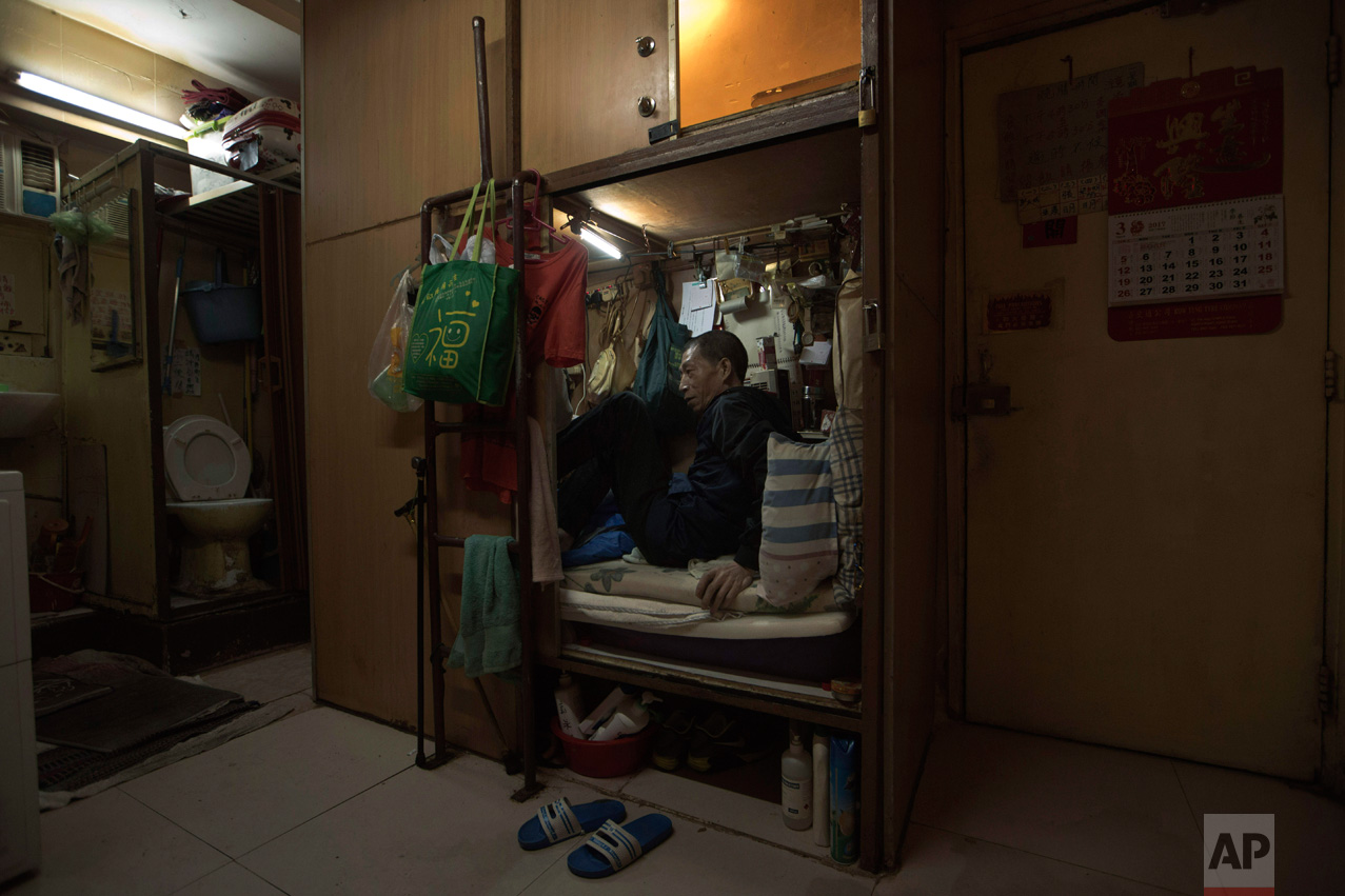  In this Thursday, March 28, 2017 photo, Wong Tat-ming, 63, sits in his "coffin home" which is next to a set of grimy toilets in Hong Kong as he pays HK$2,400 ($310) a month for a compartment measuring three feet by six feet. It's crammed with all hi