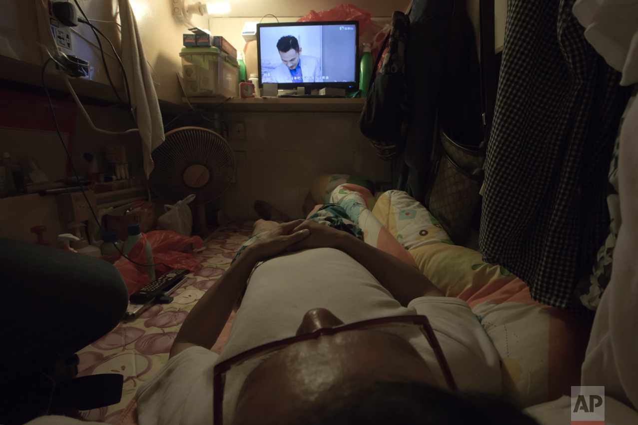  In this Thursday, May 4, 2017 photo, Simon Wong, an unemployed man, watches TV in his "coffin home" in Hong Kong. In wealthy Hong Kong, there's a dark side to a housing boom, with hundreds of thousands of people forced to live in partitioned shoebox