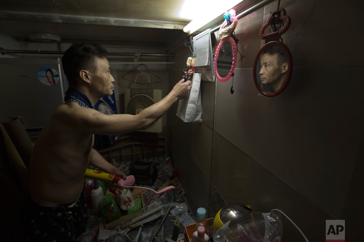  In this Thursday, May 4, 2017 photo, a resident who only gave his surname Sin, 55, tidies up the bed in his "coffin home" in Hong Kong. In wealthy Hong Kong, there's a dark side to a housing boom, with hundreds of thousands of people forced to live 