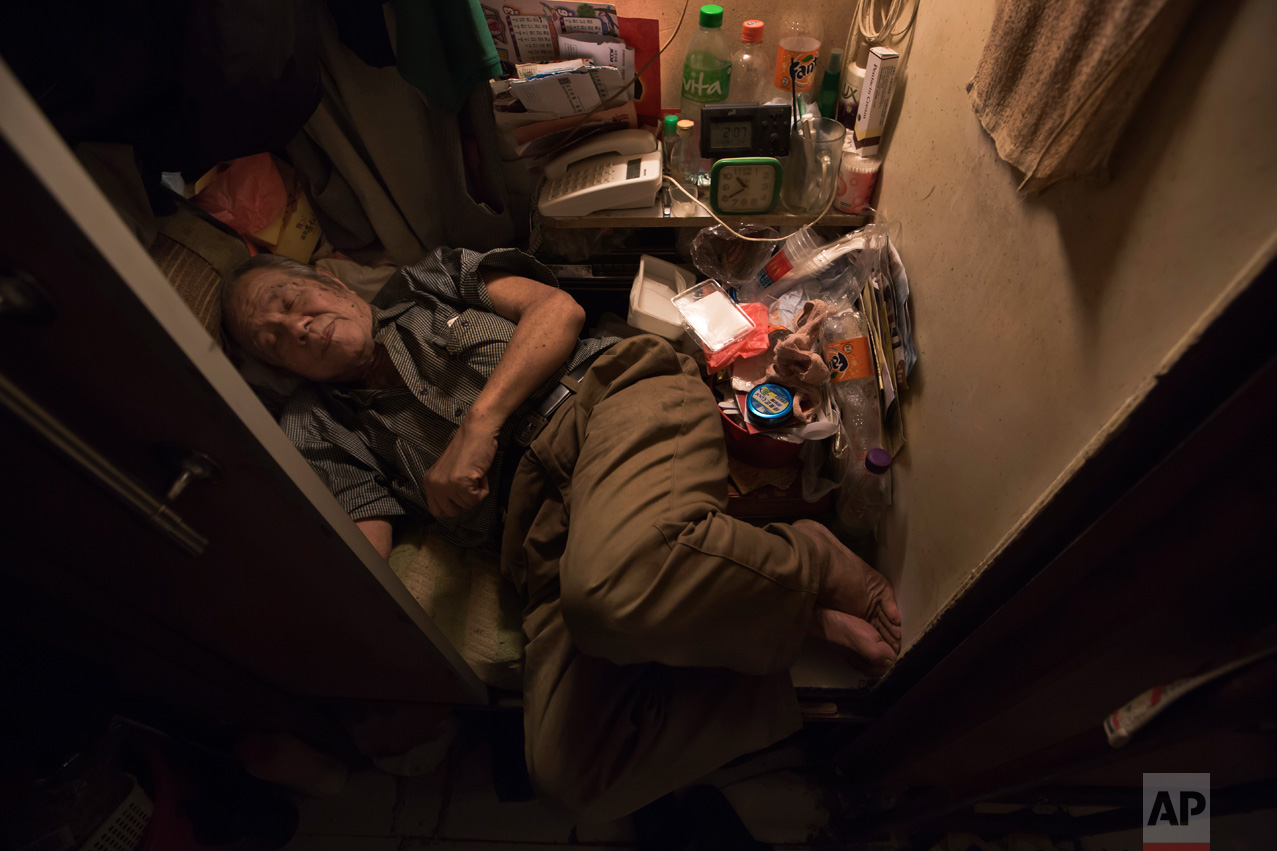  In this Thursday, March 28, 2017 photo, Cheung Chi-fong, 80, sleeps in his tiny "coffin home" where he cannot stretch out his legs in Hong Kong. In wealthy Hong Kong, there's a dark side to a housing boom, with hundreds of thousands of people forced