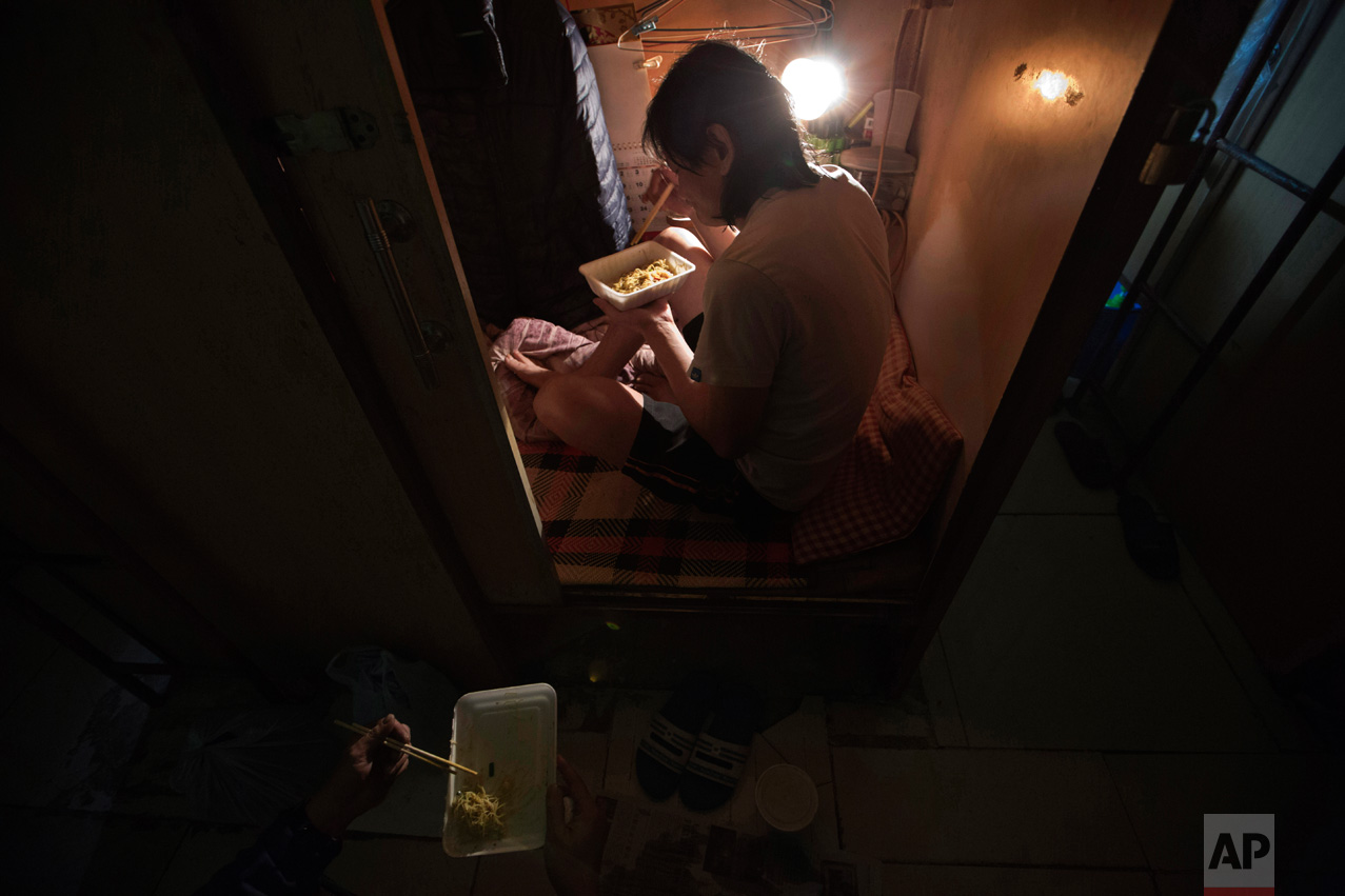  In this Thursday, March 28, 2017 photo, a resident who only gave his surname Lui, has dinner in his "coffin home" in Hong Kong. In wealthy Hong Kong, there's a dark side to a housing boom, with hundreds of thousands of people forced to live in parti