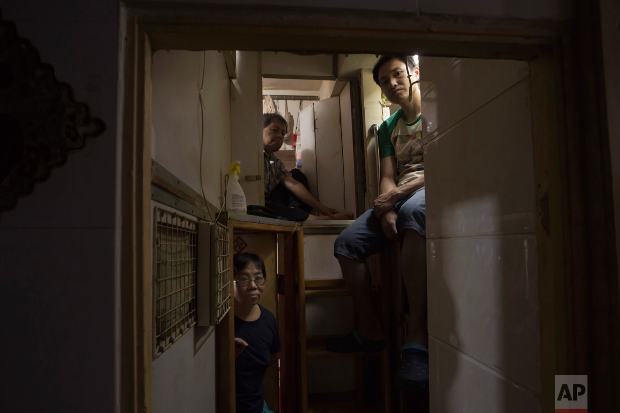  In this Thursday, May 4, 2017 photo, Hong Kong residents, who only gave their surname, Lam, top left, Wan, top right, and Kitty Au, pose at their "coffin homes" in Hong Kong. In wealthy Hong Kong, there's a dark side to a housing boom, with hundreds