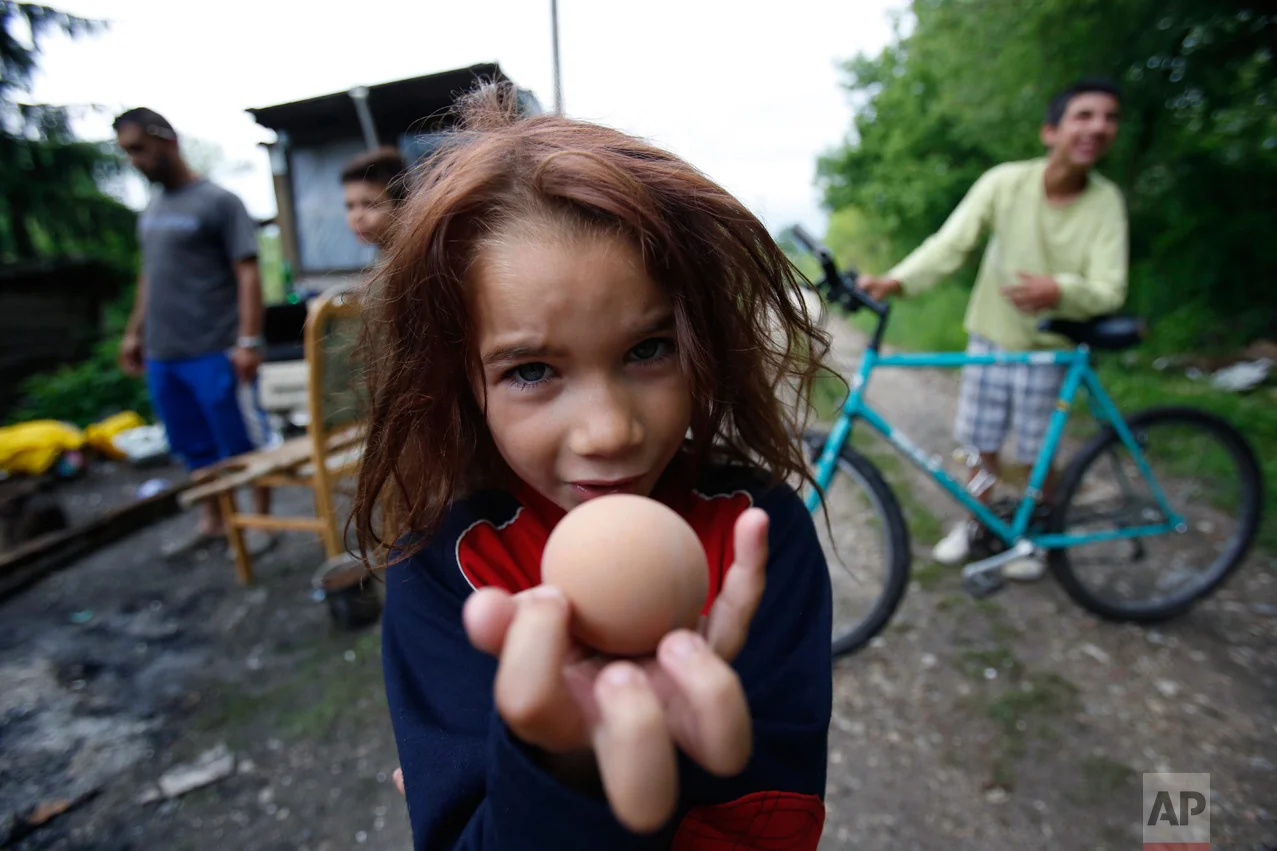 Roma girl Samira Ramic holds a boiled egg as she poses for a photo during a St. George's Day celebration with her family, in the village of Kiseljak, near Tuzla, Bosnia-Herzegovina, 140 kilometers (87 miles) north of Sarajevo, on Saturday, May 6, 2017. Members of the Roma minority community in the country celebrated their biggest holiday, St. George's Day (Djurdjevdan), marking the advent of spring, with traditional rituals such as using water from church wells to bathe and their wash hands, and cracking eggs. (AP Photo/Amel Emric)