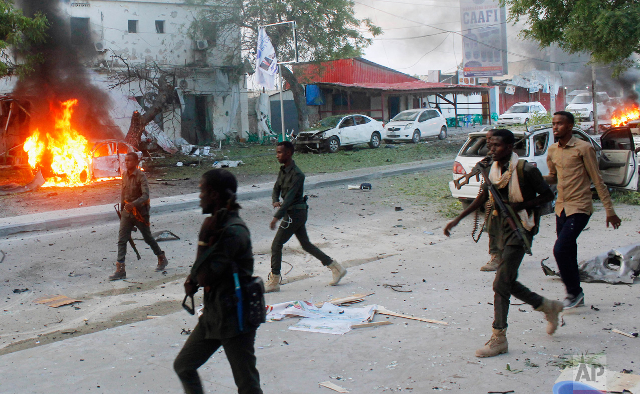 Security troops walk past burning cars after a fatal car bomb attack on a restaurant in Mogadishu, Somalia, on Monday, May, 8, 2017. Al-Shabab, Somalia's homegrown Islamic extremist rebels who are linked to al-Qaida, have claimed responsibility for the blast. Despite being ousted from most cities and towns, al-Shabab continue to carry out deadly attacks in Mogadishu and across large parts of Somalia. (AP Photo/Farah Abdi Warsameh)