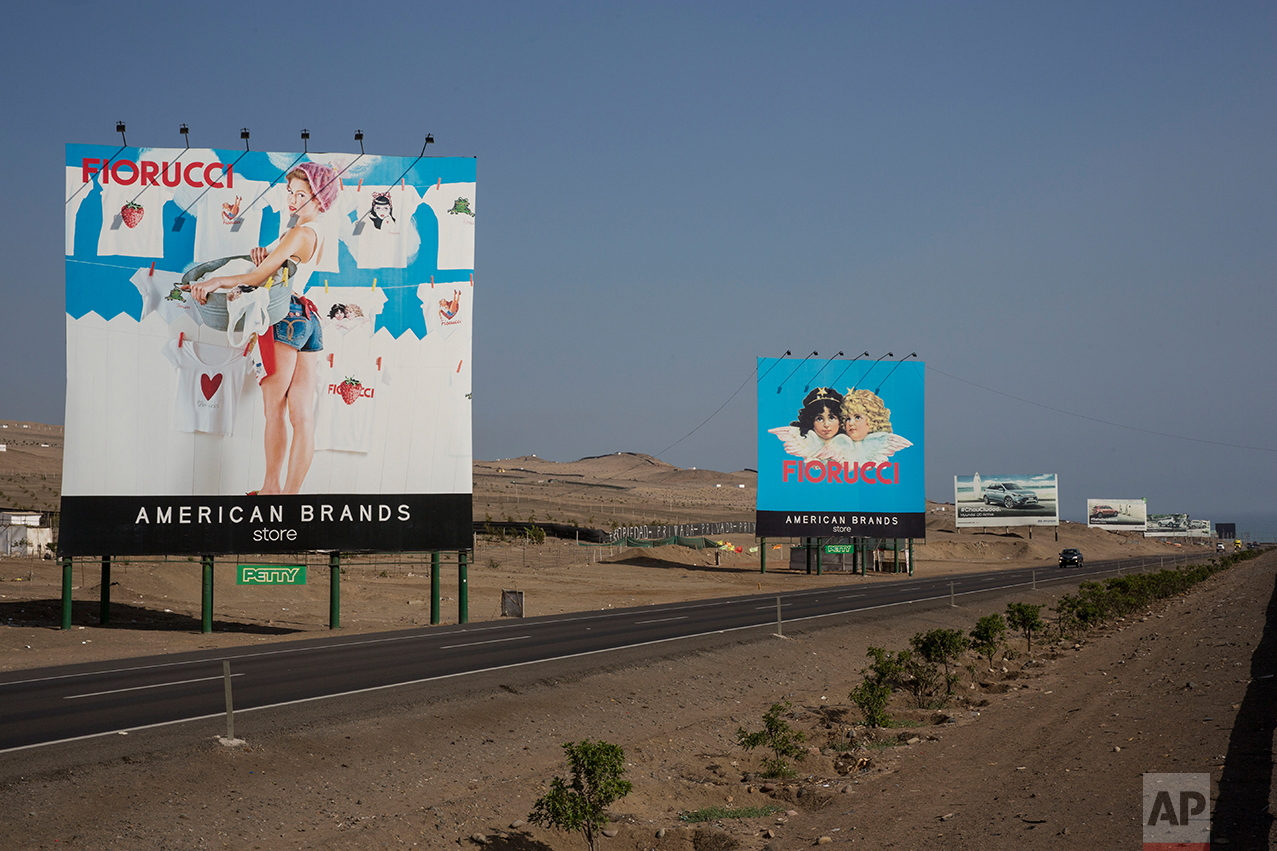  In this May 5, 2017 photo, billboards advertising a clothing store and vehicles line the Pan-American Highway on the south side of Lima, Peru. As the cars zoom by on their way to private beaches, people labor in the dusty terrain earning not enough 