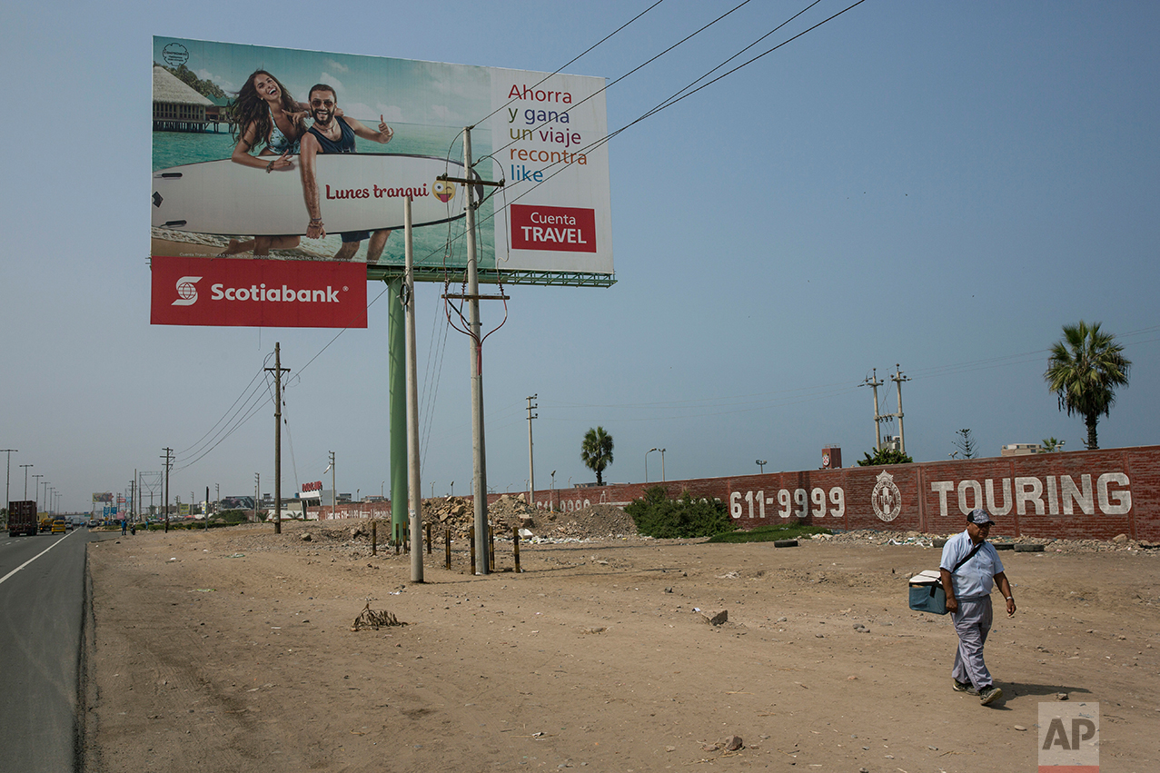  In this May 5, 2017 photo, Alejandro Sanchez carries ice cream for sale, along the Pan American Highway where a billboard advertises a bank, on the south side of Lima, Peru. Sanchez, who came here 30 years ago fleeing civil conflict in his native An