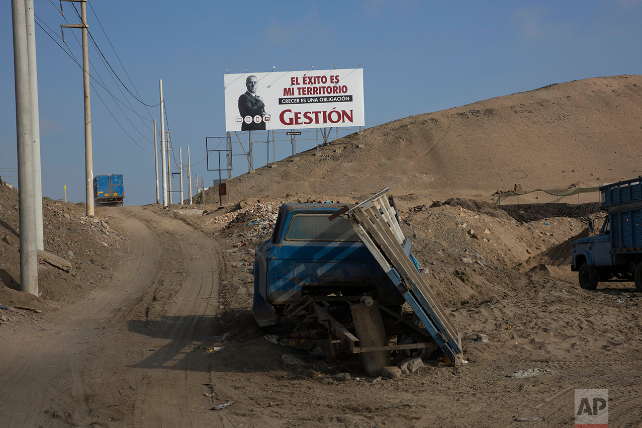  In this May 5, 2017 photo, a billboard advertising the economic magazine "Gestion" reads in Spanish: "Success is my territory. Growing is an obligation," along the Pan American Highway where a vehicle sits abandoned, on the south side of Lima, Peru,