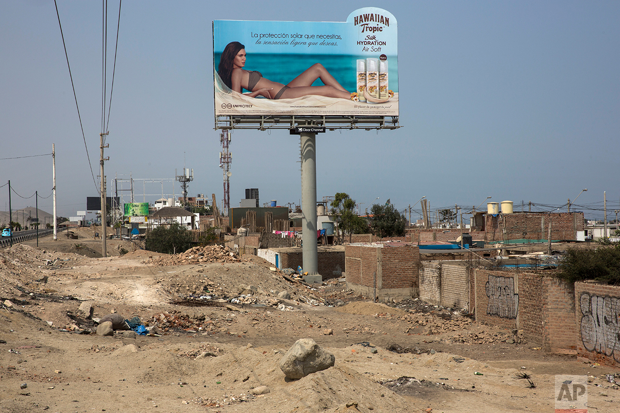  In this May 5, 2017 photo, a billboard advertising sunscreen with a woman sunbathing on a beach stands high above a poor neighborhood of cinderblock shack homes along the Pan American Highway on the south side of Lima, Peru, Friday, May 5, 2017. Wil