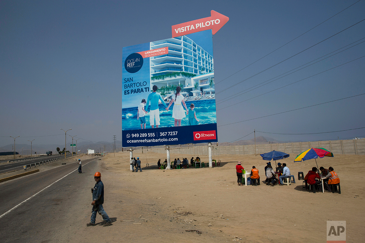  In this May 5, 2017 photo, workers eat lunch in the shade of a giant billboard advertising condos for sale, in a poor neighborhood on the south side of Lima, Peru, Friday, May 5, 2017. The billboards advertise glamorous apartments and other luxury i