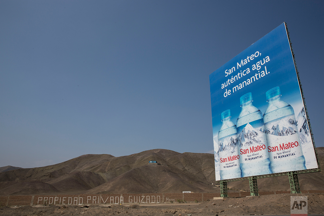  In this May 5, 2017 photo, a billboard advertising spring water stands along the Pan American Highway on the south side of Lima, Peru. Trash is scattered around the area where people live in homes without potable water and adequate public services, 