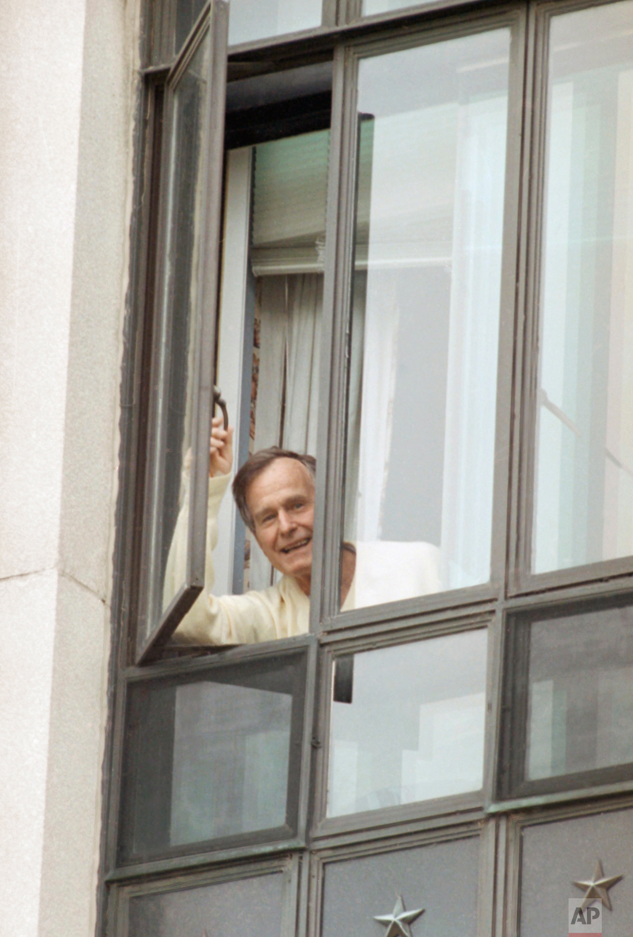  President George Bush talks with reporters from his window at Bethesda Naval Medical Center in Bethesda, Md., May 5, 1991. "Don't worry about me," the president shouted to the reporters. The president's heartbeat is still irregular, however tests ha