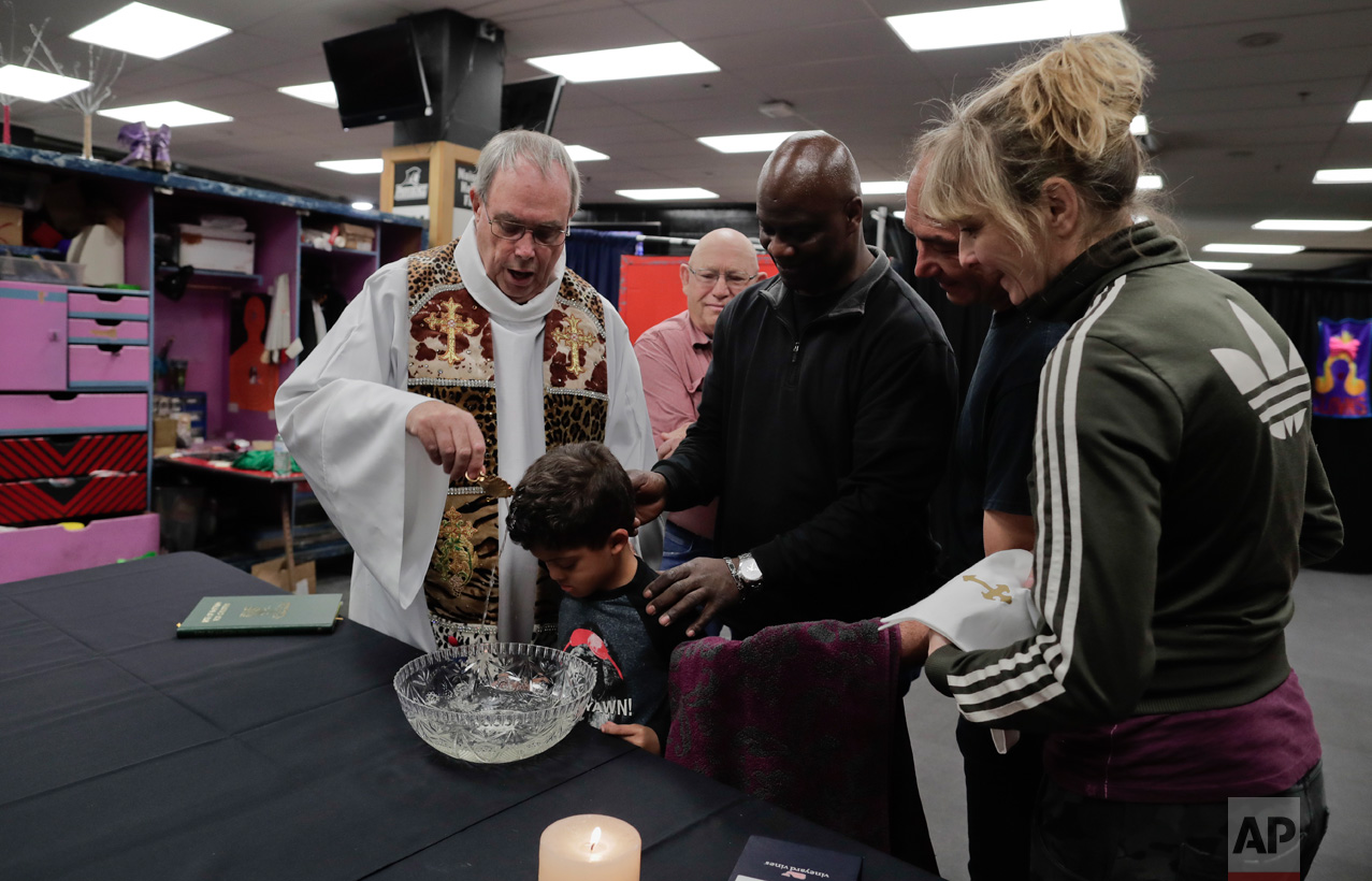  Rev. Jerry Hogan, left, of the U.S. Conference of Catholic Bishops' Circus and Traveling Shows Ministry, leads a baptism service for 6-year-old Eddie Strickland, the son of Jimmie Strickland, a member of the crew before a Ringling Bros. circus show 