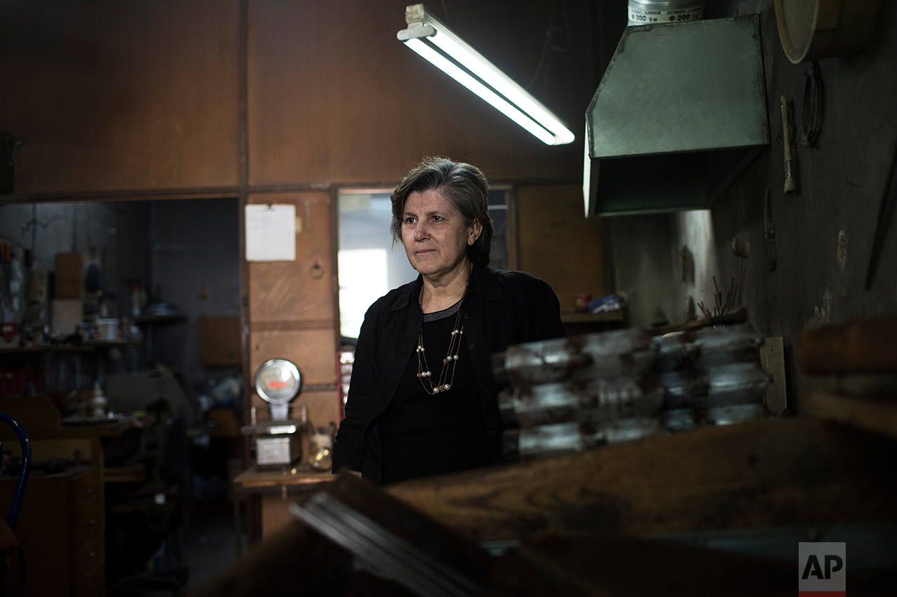  In this Thursday, May 11, 2017 photo, Greek pensioner Paraskevi Koliambi, 60, a widow and former silversmith, poses during a visit to her son's workshop in Athens. "I see it as uncertain, the future," Koliambi said. "We're trying to hold on. My son 