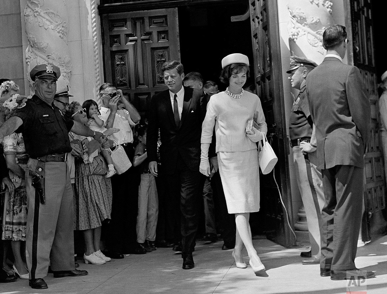  President John F. Kennedy and first lady Jacqueline Kennedy leave St. Edward's Catholic Church in Palm Beach, Fla., after attending Easter Sunday services, April 2, 1961. At left, a policeman stands in front of part of crowd that gathered to see the