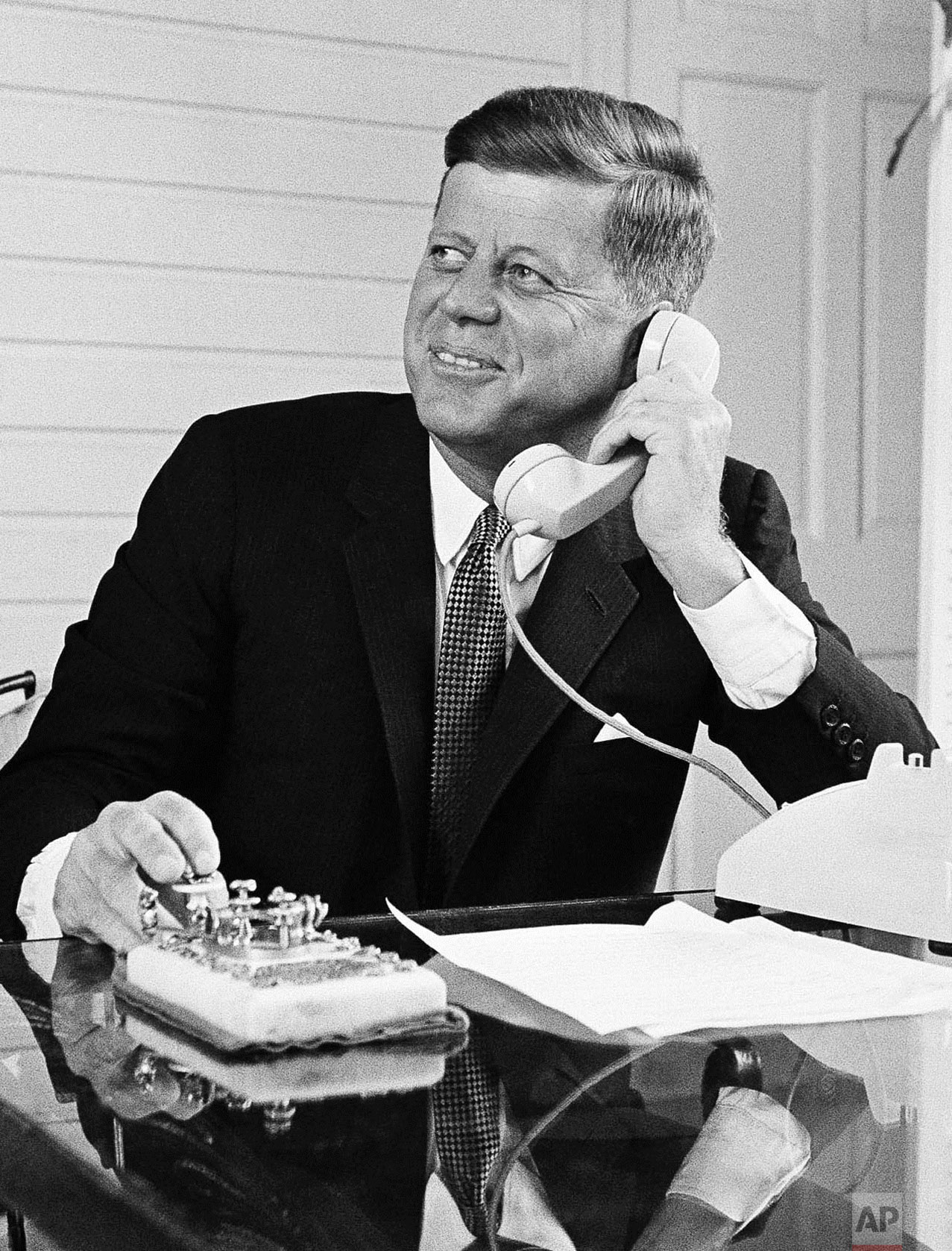  President F. Kennedy presses a gold telegraph key as he speaks over the telephone to open the Seattle World's Fair in Palm Beach, Fla. on April 21, 1962. By pressing the key, the president focused an antenna at Andover, Maine and a Navy radio telesc