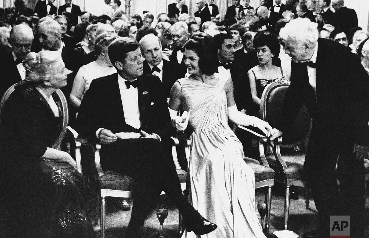  In this April 30, 1962 photo, President John F. Kennedy, sitting with his wife Jacqueline, looks on as poet Robert Frost, right, and Mrs. Richard J. Walsh (Pearl Buck) exchange greetings in the East Room of the White House in Washington. The first f