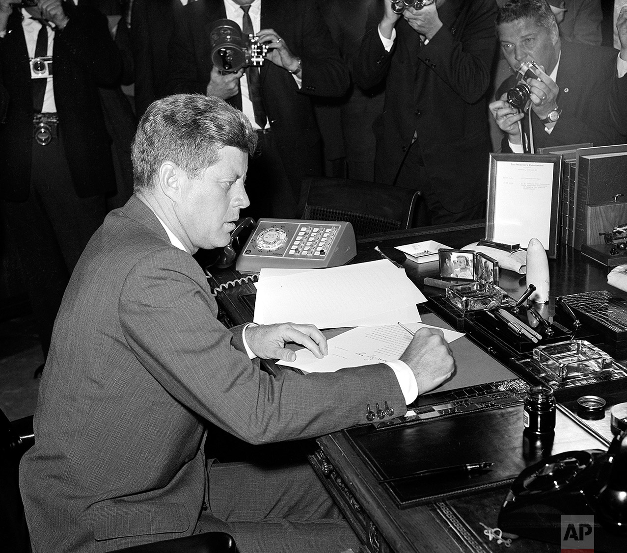  U.S. President John F. Kennedy is surrounded by photographers, as he sits at his desk in the White House, in Washington, D.C., on October 23, 1962, shortly after signing a presidential proclamation concerning the Cuba crisis. (AP Photo) 