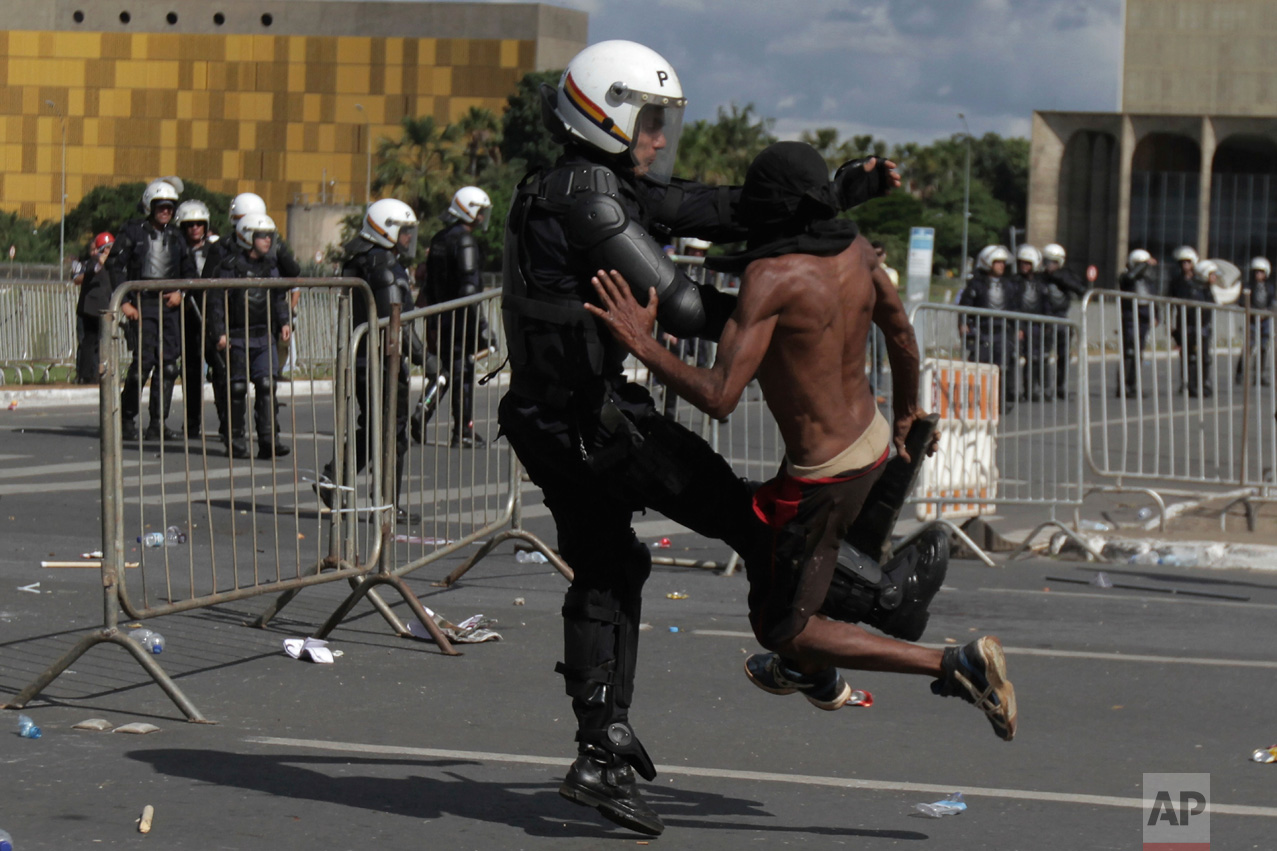  A demonstrator clashes with a police officer during an anti-government protest in Brasilia, Brazil, Wednesday, May 24, 2017. Brazil's president ordered federal troops to restore order in the country's capital following the evacuation of some ministr