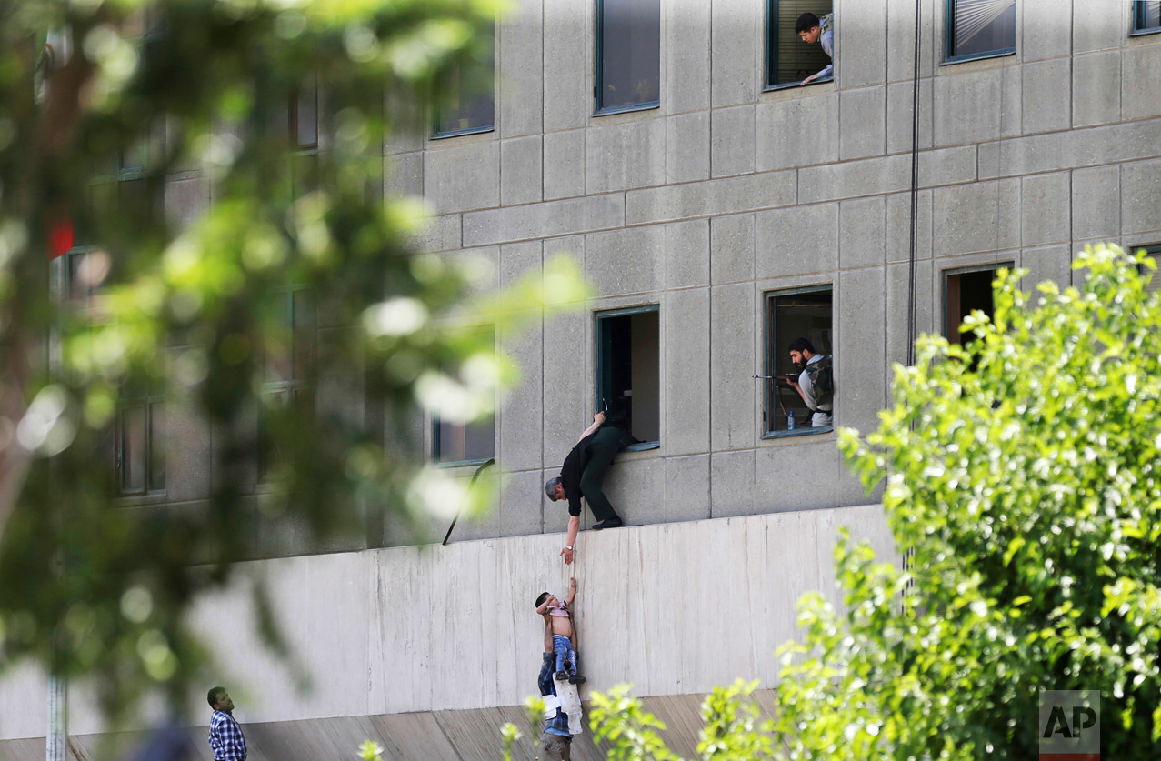 A man hands a child to a security guard after an assault on the parliament building in Tehran, Iran, on Wednesday, June 7, 2017. Suicide bombers and gunmen simultaneously targeted the legislature and a shrine of late founder of the Islamic Republic Ayatollah Ruhollah Khomeini. (Fars News Agency, Omid Vahabzadeh via AP)