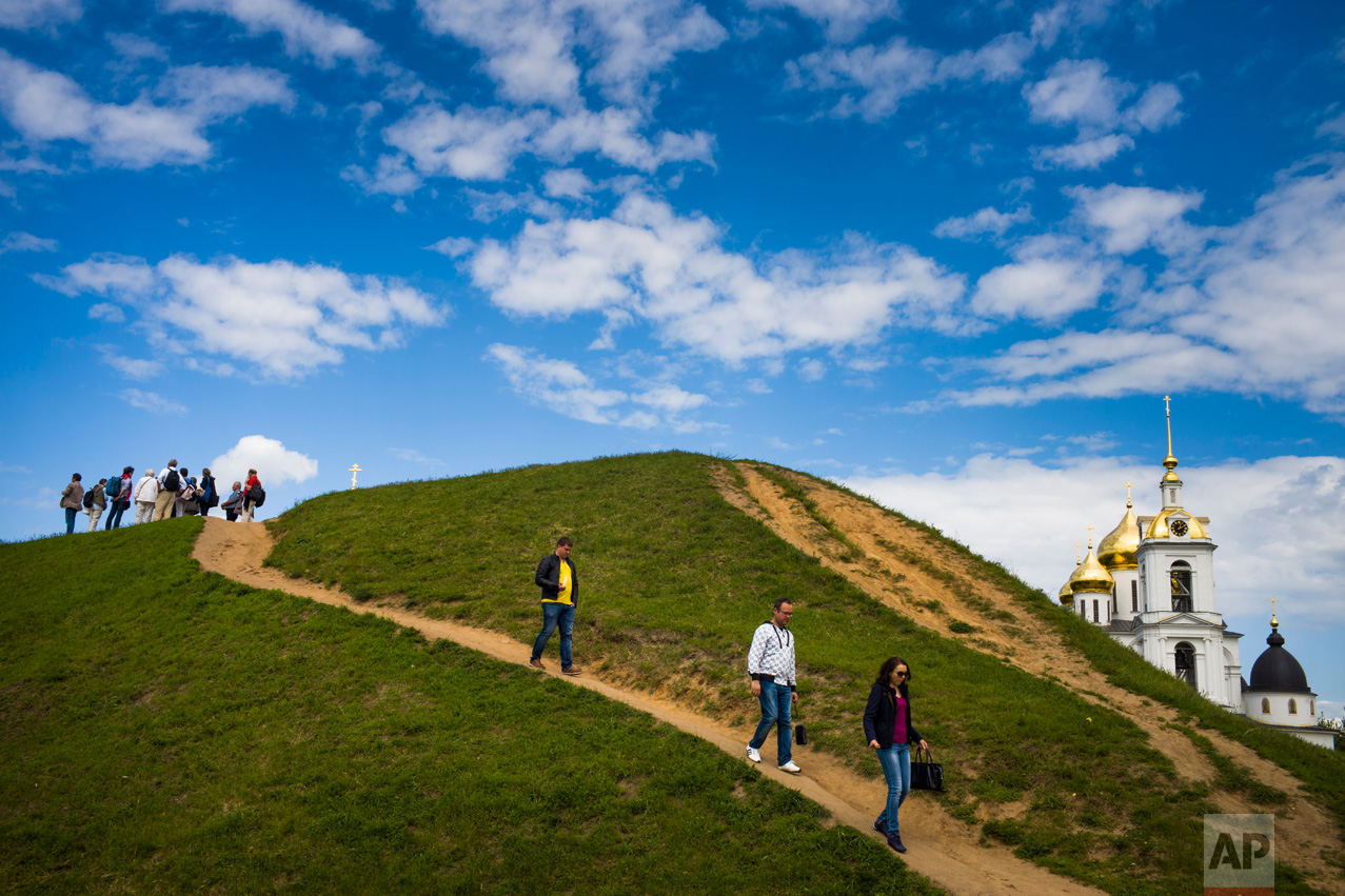 Tourists walk down from a hill near an Assumption Cathedral built in the 16th Century in the small Russian town of Dmitrov, Russia, 75 kilometers (47 miles) north from Moscow on Sunday, June 11, 2017. (AP Photo/Alexander Zemlianichenko)