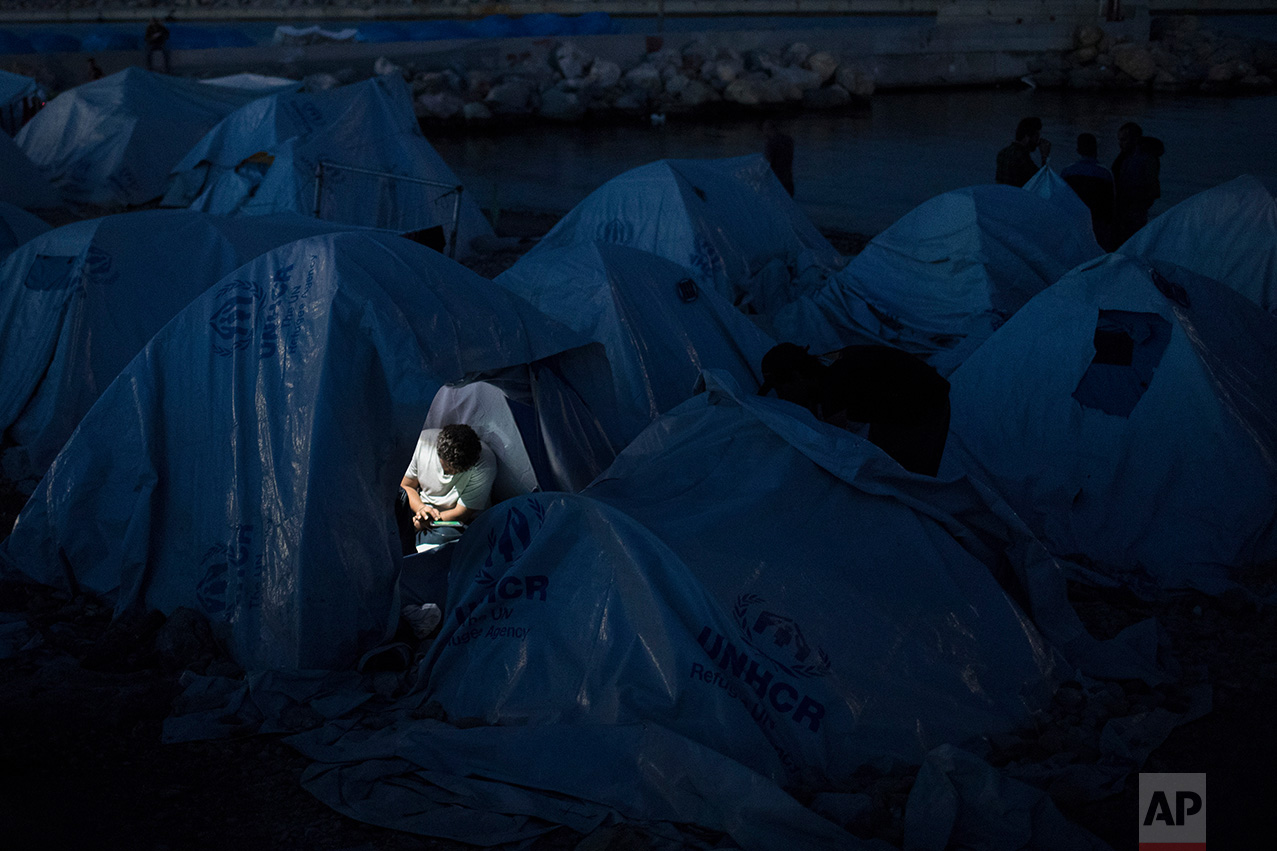  In this June 9, 2017 photo, a refugee looks at his tablet inside a tent that he uses as a shelter at a beach near the Souda refugee camp, on Chios island, Greece. (AP Photo/Petros Giannakouris) 