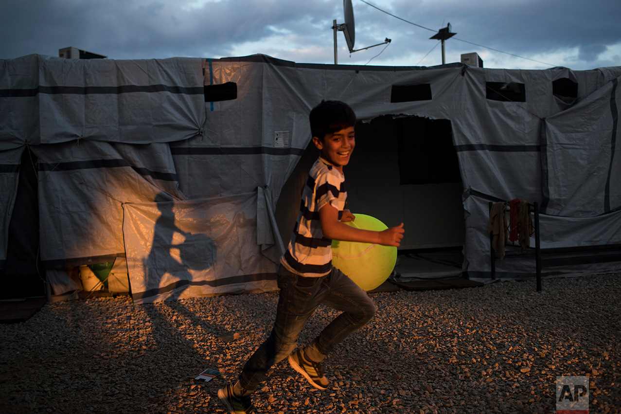  In this May 29, 2017 photo, a Syrian boy runs as he carries a giant tennis ball at the refugee camp of Ritsona about 86 kilometers (53 miles) north of Athens. (AP Photo/Petros Giannakouris) 
