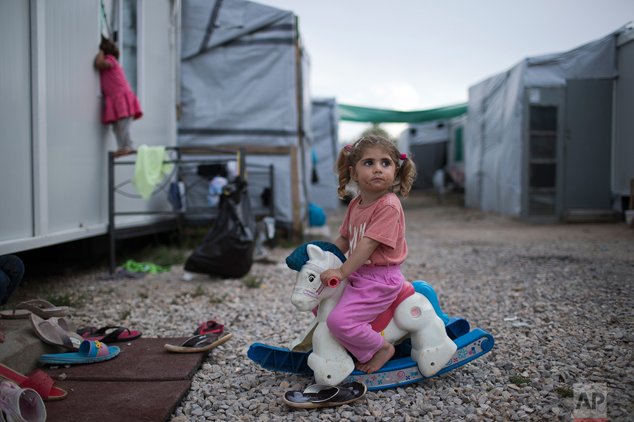  In this May 25, 2017 photo, three-year-old Ragika from Syria plays with a plastic toy horse at the refugee camp of Ritsona about 86 kilometers (53 miles) north of Athens. According to the UN Refugee agency there are more than 21 millions refugees ar